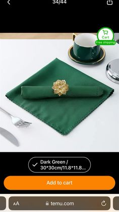 a green napkin with a gold flower on it next to a cup and saucer