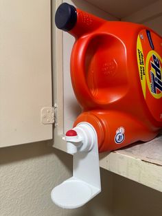 an orange plastic jug is on the shelf next to a cup holder