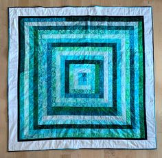 a blue and green quilt on a wooden floor