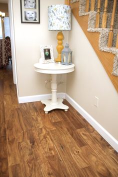 a white table sitting under a stair case next to a wooden bannister with pictures on it