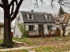 a white house sitting on the side of a road next to a leaf covered yard