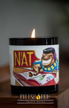 a lit candle sitting on top of a wooden table next to a sign that says natt