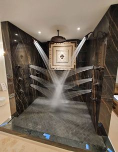 a bathroom with black marble walls and flooring that has lights coming from the ceiling