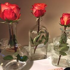 three vases with roses in them sitting on a table