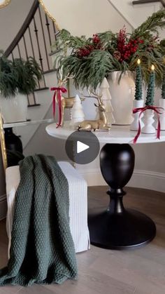 a living room filled with christmas decorations on top of a white table next to a stair case