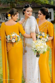 three women in yellow dresses standing next to each other and one woman is holding flowers