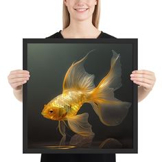 a woman holding up a goldfish art print in front of her face and smiling at the camera