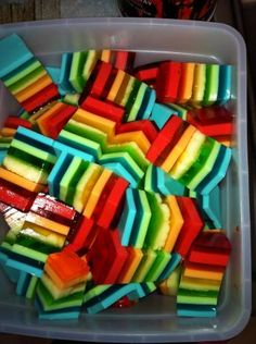 a plastic container filled with lots of rainbow colored candy bars on top of a table