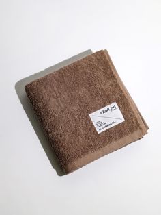 a brown towel sitting on top of a white table next to a black and white tag