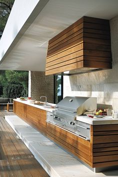 an outdoor kitchen with wooden cabinets and counter tops