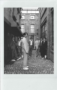 black and white photograph of men standing in an alleyway between two buildings, with one man looking at the camera