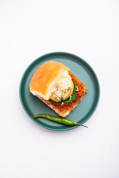 a sandwich on a blue plate with a green pepper