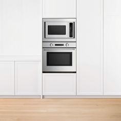 a stainless steel oven and microwave in a white kitchen with wood flooring on the side