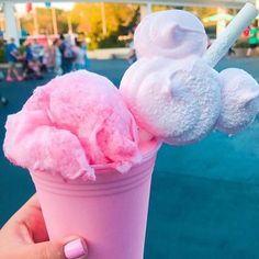 someone holding up a pink ice cream sundae with marshmallows on top