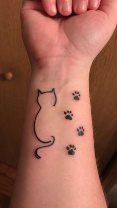 a woman's wrist with a cat and paw prints on the left side of her arm