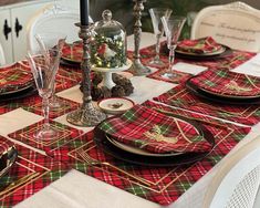 the table is set for christmas dinner with red and green plaid napkins on it