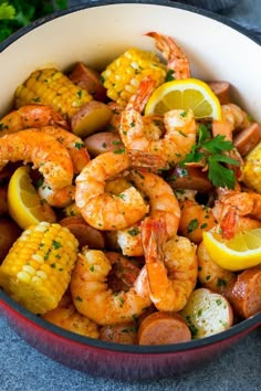 a bowl filled with shrimp and corn on the cob, garnished with parsley