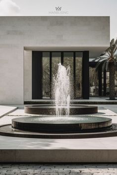 a fountain in front of a building with palm trees