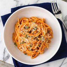 a white bowl filled with pasta and parmesan cheese on top of a blue napkin