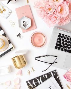 an open laptop computer sitting on top of a desk next to pink flowers and other items