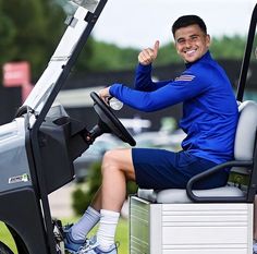 a man sitting in the driver's seat of a golf cart giving a thumbs up