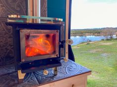 a stove that is sitting on top of a table in front of some grass and water