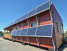 a red building with solar panels on the roof and windows in place to allow shade