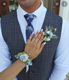 a man and woman are dressed up with flowers on their wrist ties, one is holding the other's hand