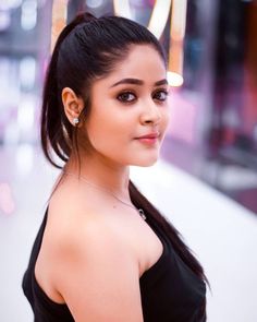 a beautiful young woman standing in front of a neon sign with her hair pulled back