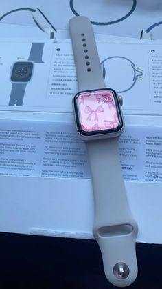 an apple watch sitting on top of a box with its display showing the pink flower