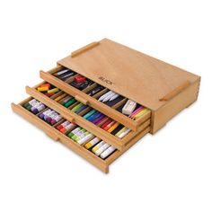 three wooden drawers with different colored crayons in them and the bottom drawer open