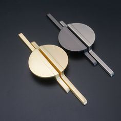 two paddles and a round object on a black surface, one is gold and the other is silver