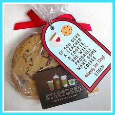 a cookie wrapped in plastic next to a starbucks gift card with a red ribbon on it