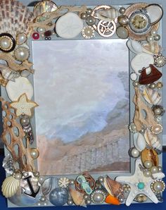 a frame with shells, seashells and other things on the bottom half of it