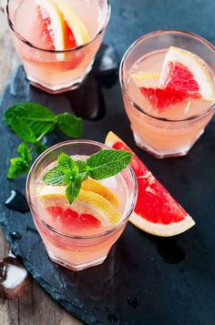 two glasses filled with watermelon, lemon and mint garnish on a slate tray