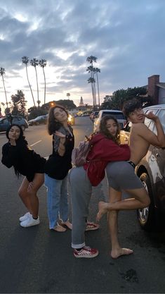 four people standing in front of a parked car