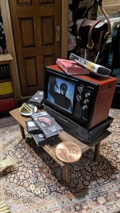 an old tv sitting on top of a coffee table next to a pile of books