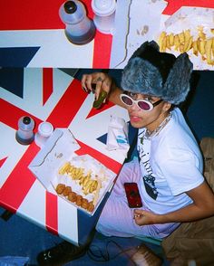 a woman sitting at a table in front of a box of food with french fries on it