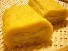 two pieces of yellow food sitting on top of a bamboo table next to chopsticks