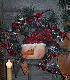 a christmas wreath with a santa hat on it and a candle in front of it