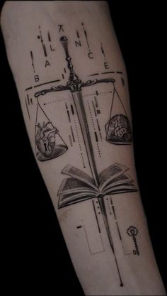 a tattoo with books and scales on it