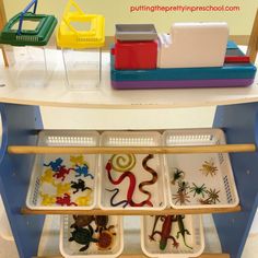 three trays filled with different types of toys on top of a wooden shelf next to plastic containers