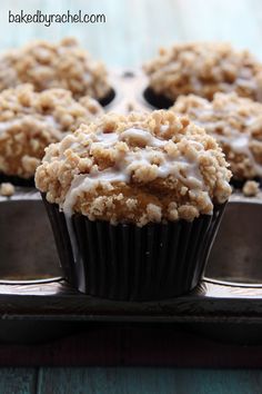 cupcakes with white icing and crumbs sitting in a metal pan