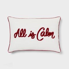 a red and white pillow with the word all is calm embroidered on it's side