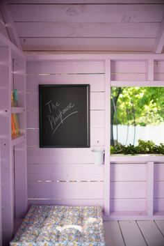 there is a chalkboard in the corner of this room with purple walls and wood flooring