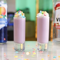 two glasses filled with ice cream and sprinkles next to bottles of soda