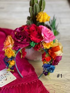 a bouquet of flowers sitting on top of a pink blanket next to a cactus plant