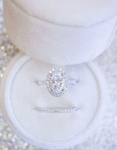 an engagement ring sits on top of a white box with silver glitter around the edges