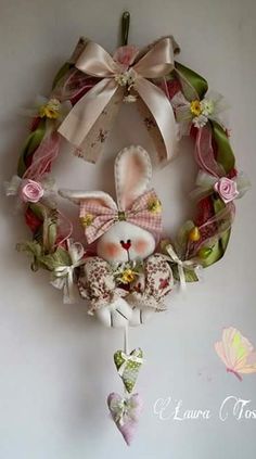 a wreath hanging on the side of a wall with flowers and bunny ears attached to it