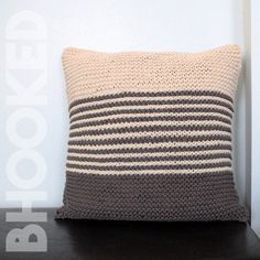 a crocheted pillow sitting on top of a wooden table next to a white wall